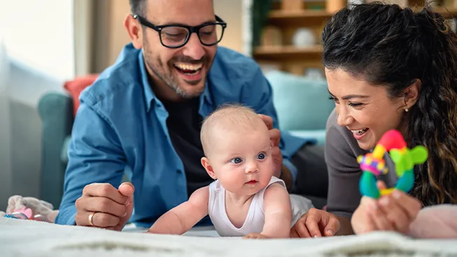 Dad and mom playing with baby during tummy time