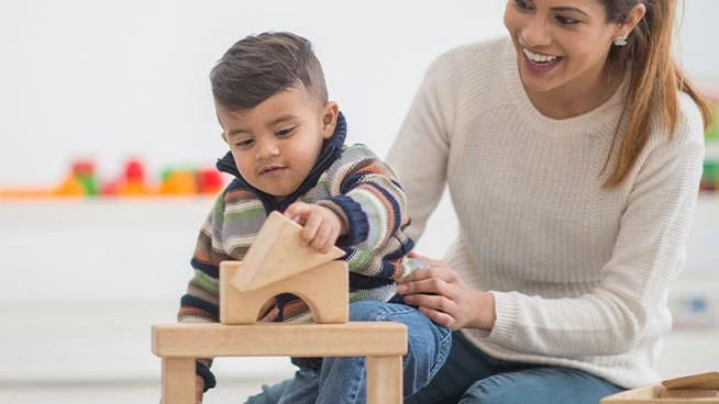 Mom and toddler son playing with blocks