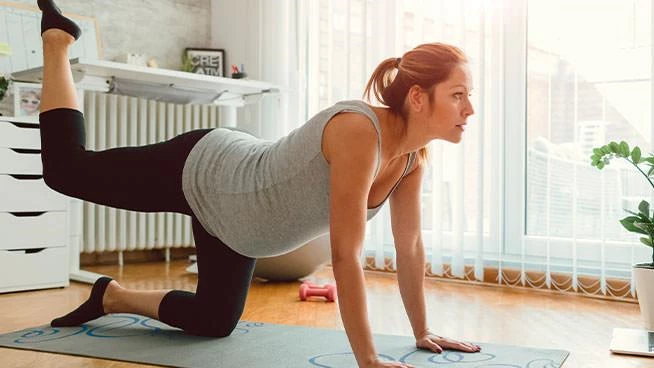 Pregnant mom doing donkey kick exercise on the floor