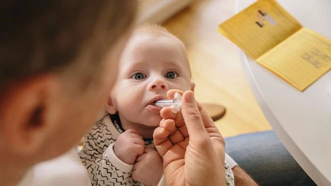 Parent giving baby vitamin drops