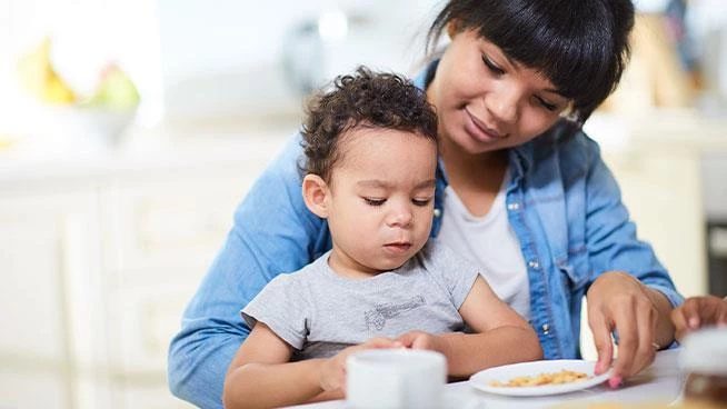 Toddler sitting on mom's lap and eating snacks