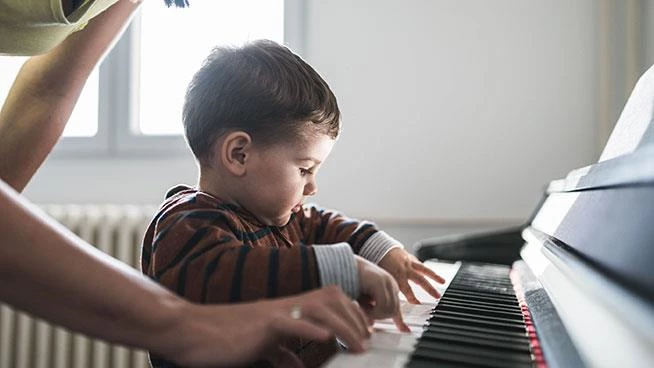Niño pequeño tocando el piano con sus padres ayudando