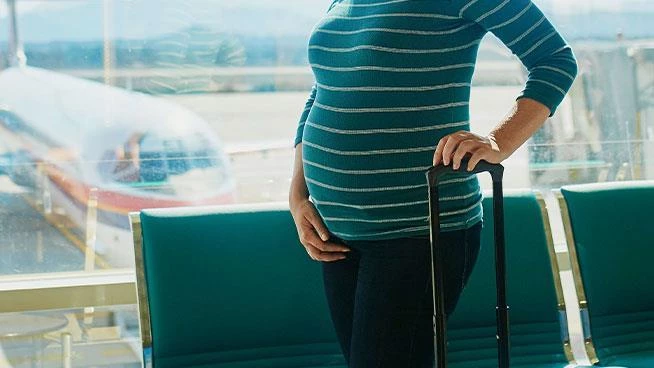 Expecting mom with a suitcase standing in the airport