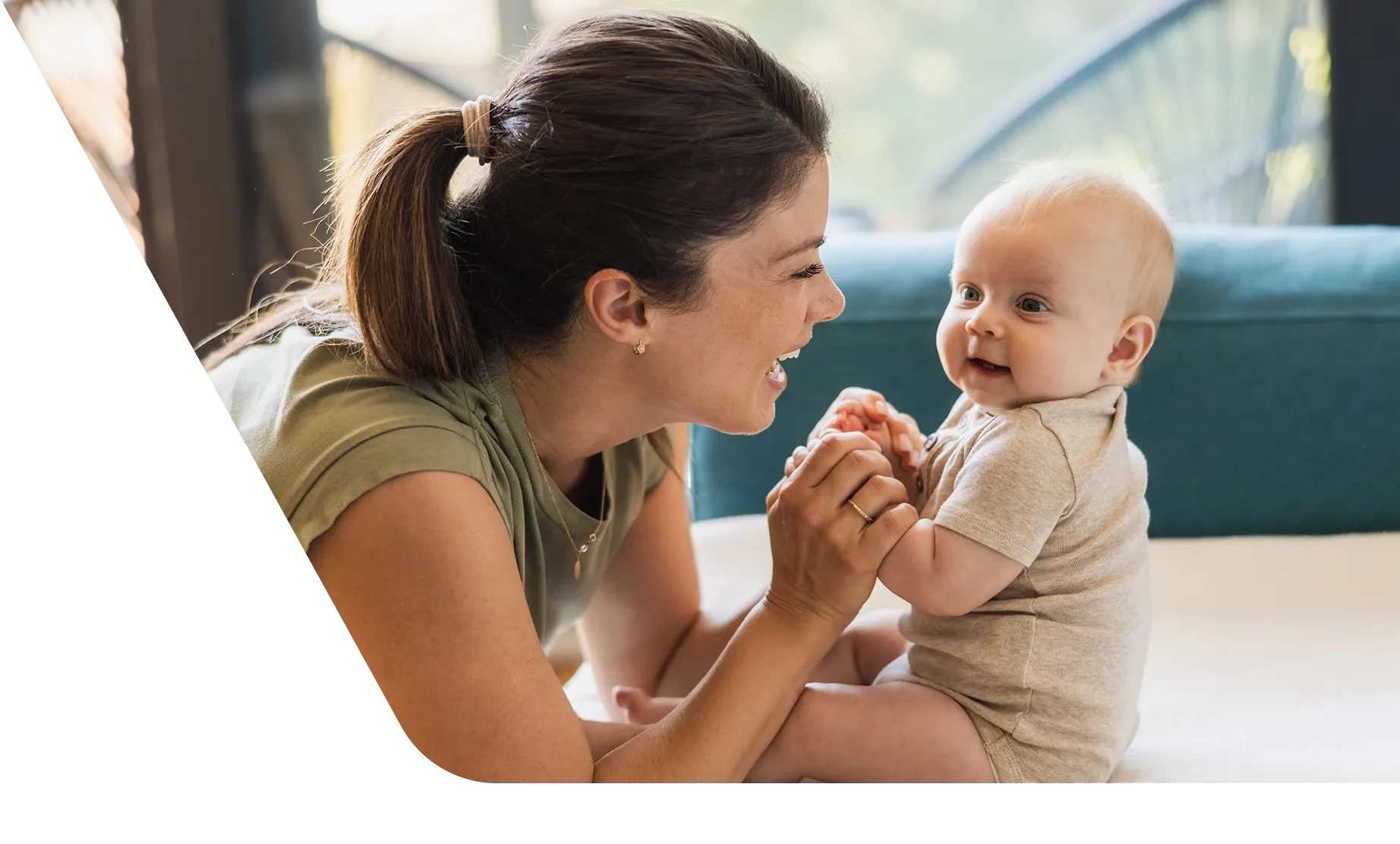 Mom holding baby's hands while baby learns to sit up