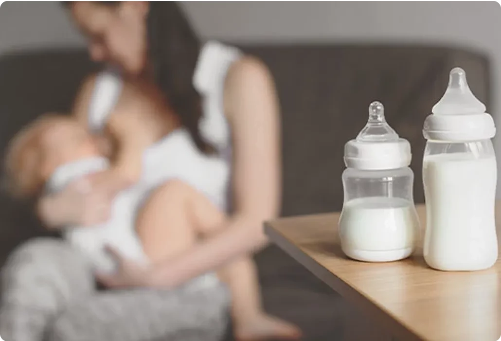 Mom feeding baby with a bottle nearby