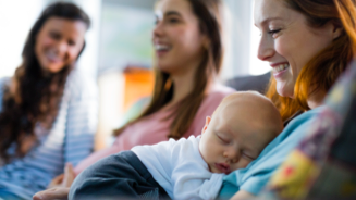Mom holding her infant while hanging out with friends