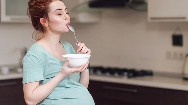 Pregnant woman eating ice cream out of a bowl