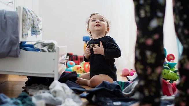 Infant sitting in messy bedroom
