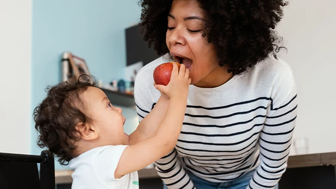 Toddler son holding an apple up to mom
