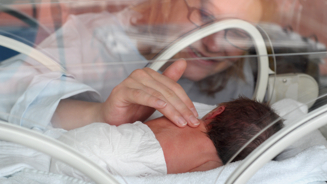 New mom touching preemie in the NICU