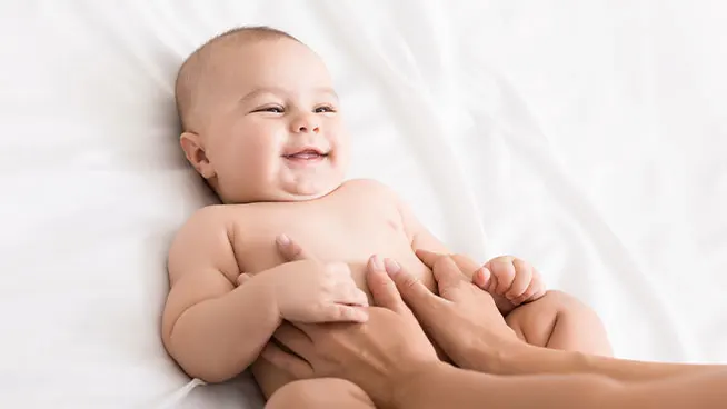 Newborn smiling as parent put hands on their belly