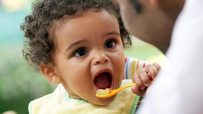Niño feliz comiendo una cucharada de comida