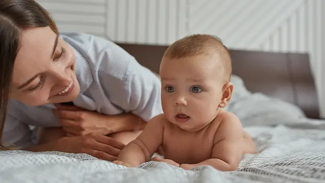 Baby getting tummy time while mom watches and encourages them