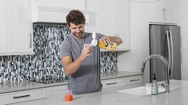 Dad in the kitchen pouring liquid formula into a bottle