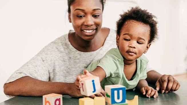 Mamá y niño jugando con bloques con letras