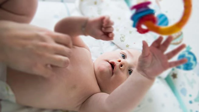 Baby playing with toy ring while laying on the floor