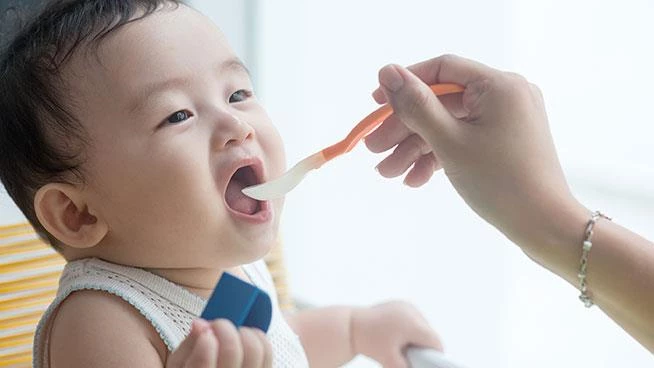 Mom spoon-feeding her baby