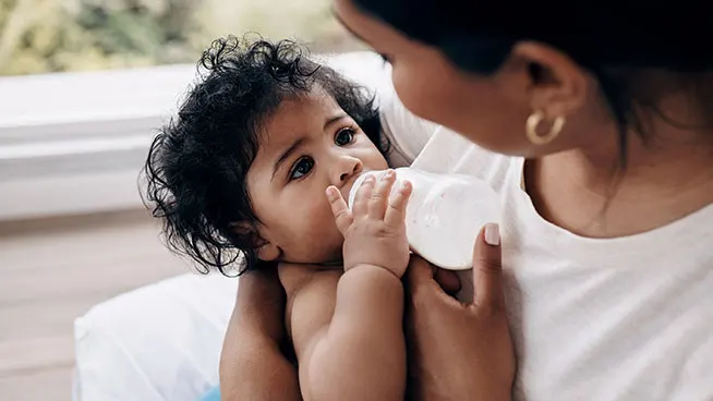 Mother cradling baby and feeding with a bottle