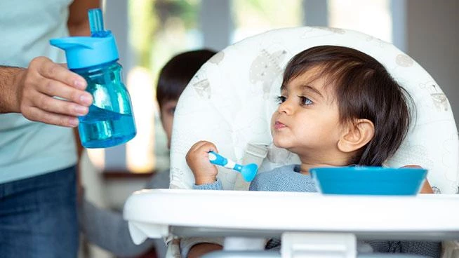 Papá le entrega al niño un cuyp para sorber