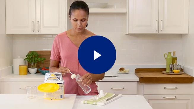 Image of woman making a bottle with play button overlay