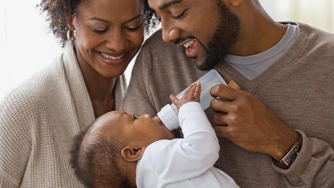 New dad and mom bottle feeding their baby