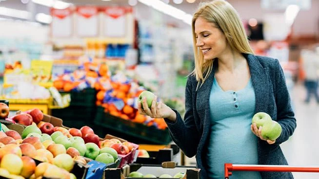 Mujer embarazada de compras con manzanas verdes