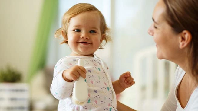 Bebé sonriente sostenido por mamá