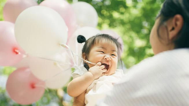Niño feliz sosteniendo globos con su mamá