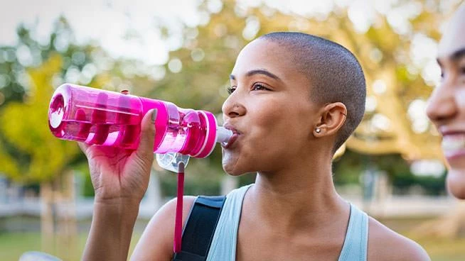 Woman drinking from a pink water bottle