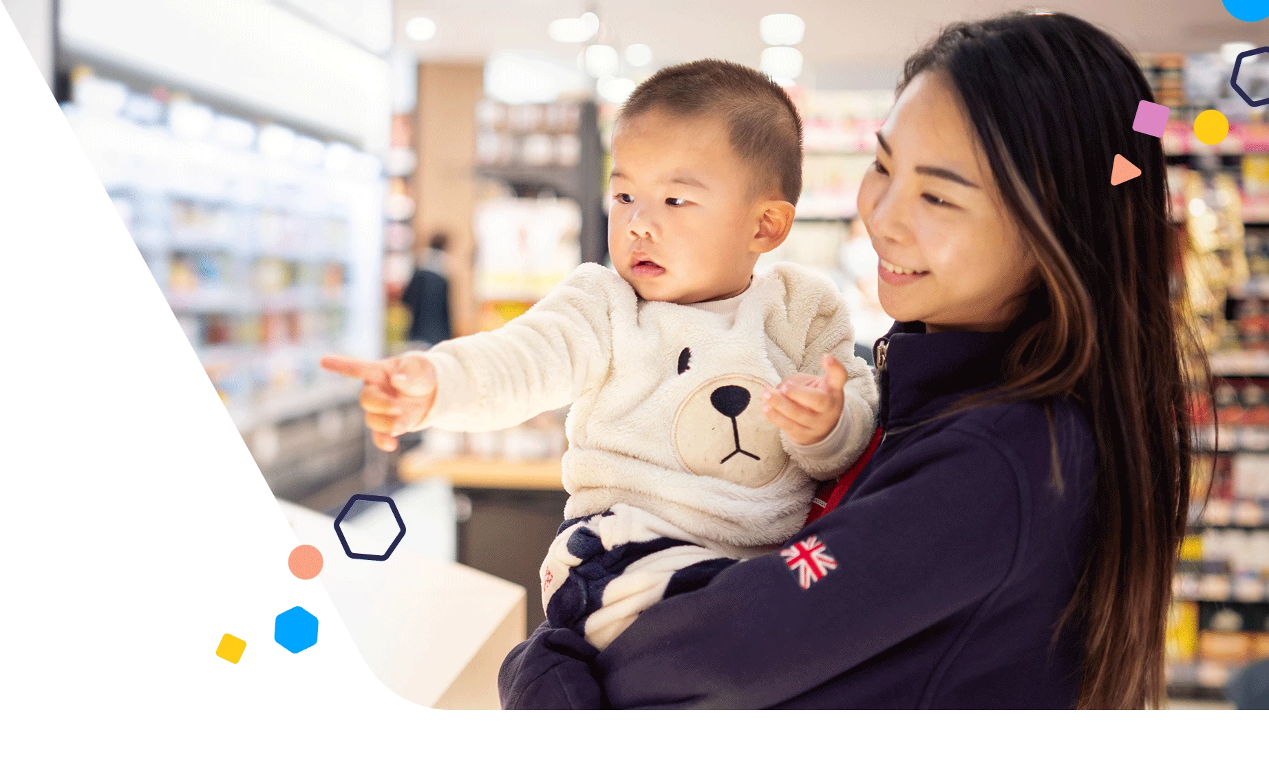 Mamá sosteniendo a un niño pequeño que señala la comida en el supermercado