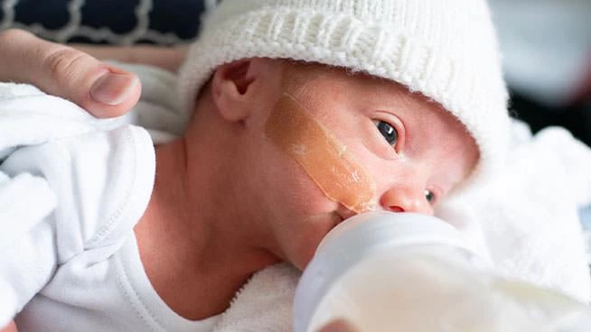 Premature baby drinking from a baby bottle