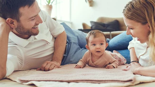 Mamá y papá jugando en el suelo con su bebé
