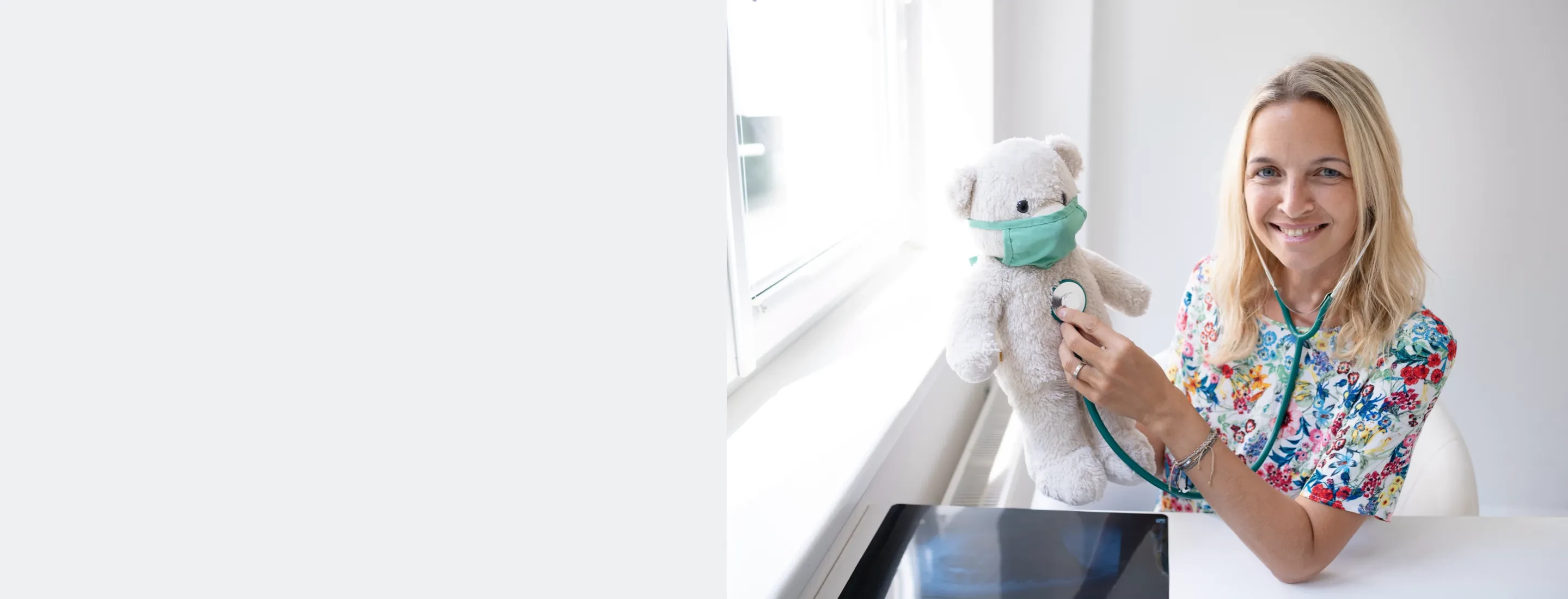 Nurse holding a stethoscope to a stuffed bear