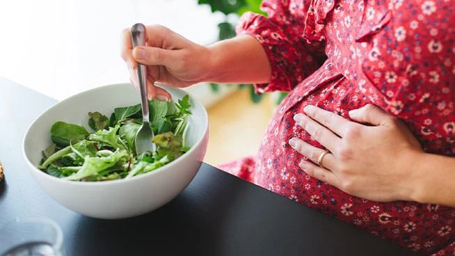 Mujer embarazada comiendo una ensalada