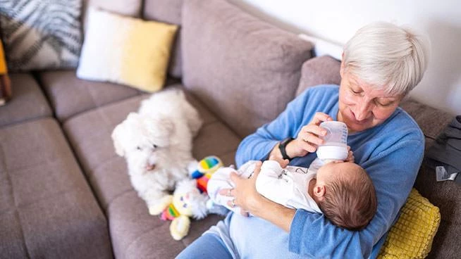 Grandma bottle-feeding baby on the couch