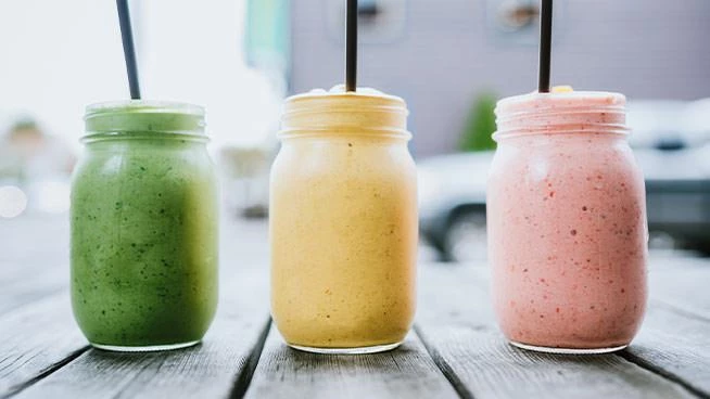 Three colorful tropical fruit smoothies with straws