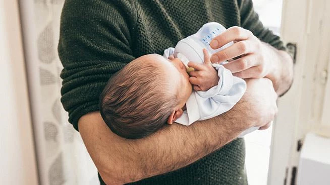 Dad bottle feeding his newborn