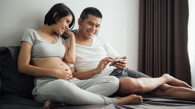 Expecting couple sitting and looking at phone