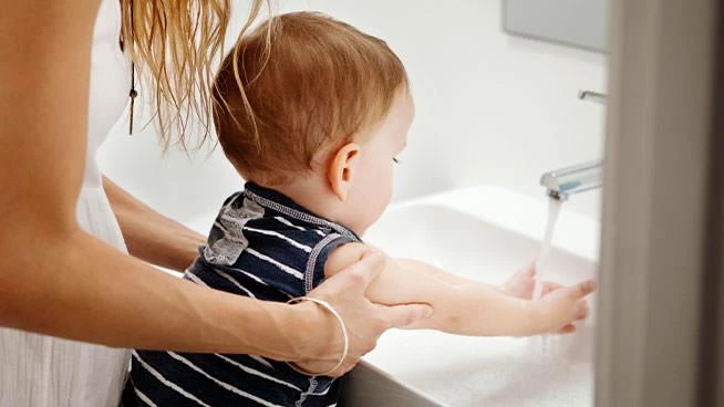 Mom helping toddler son wash his hands