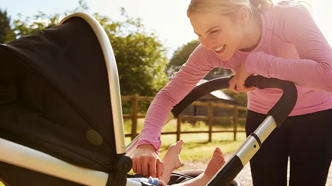 Mom smiling at baby in a stroller during their walk