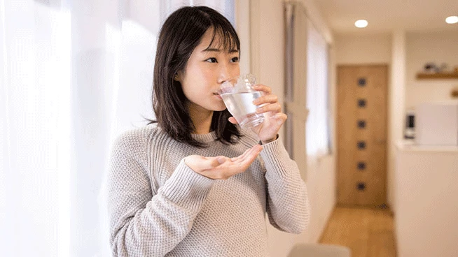 Pregnant mom drinking water and holding prenatal vitamins