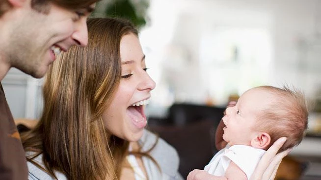 Dad and mom holding newborn and smiling