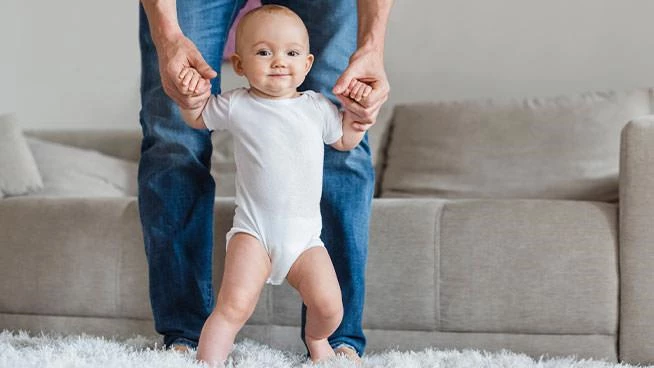 Bebé paseando con la ayuda de su papá