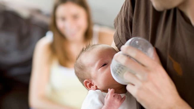 Dad feeding a bottle to newborn baby