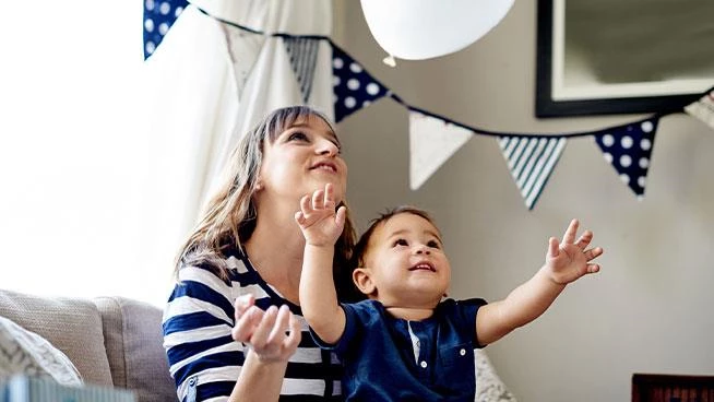 Niño sentado en el regazo de su madre mirando una pancarta colorida