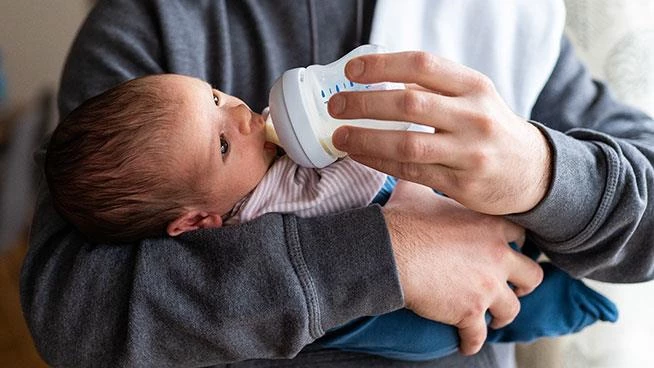 Dad bottle feeding newborn