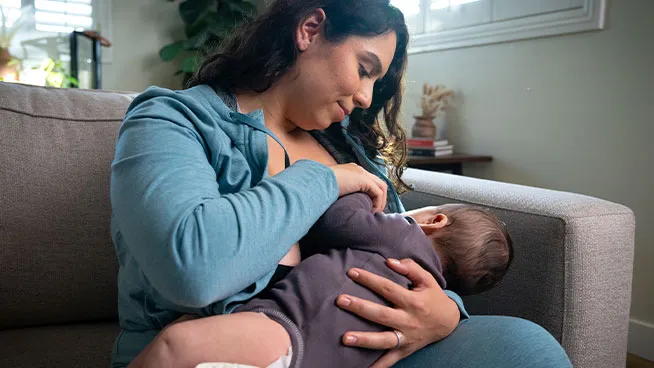 Smiling mother breastfeeding baby in a position to prevent acid reflux.