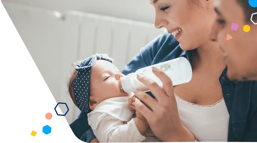 Mamá dándole un biberón al bebé con papá sonriendo cerca