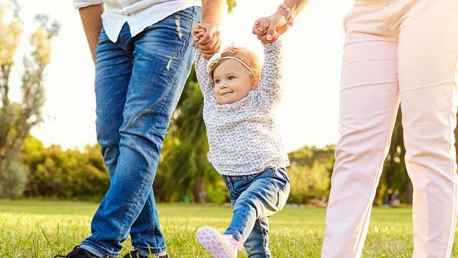 Mamá y papá caminando con su bebé afuera.