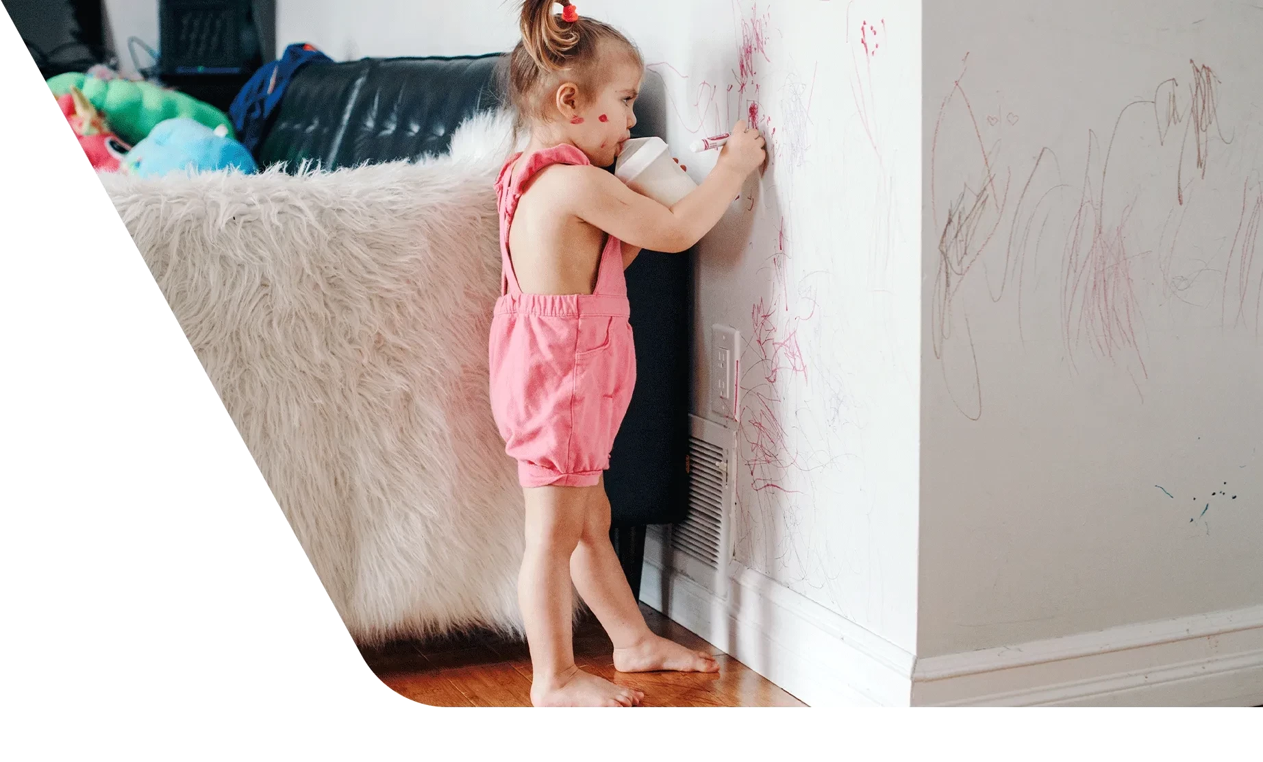 Toddler with sippy cup coloring on wall